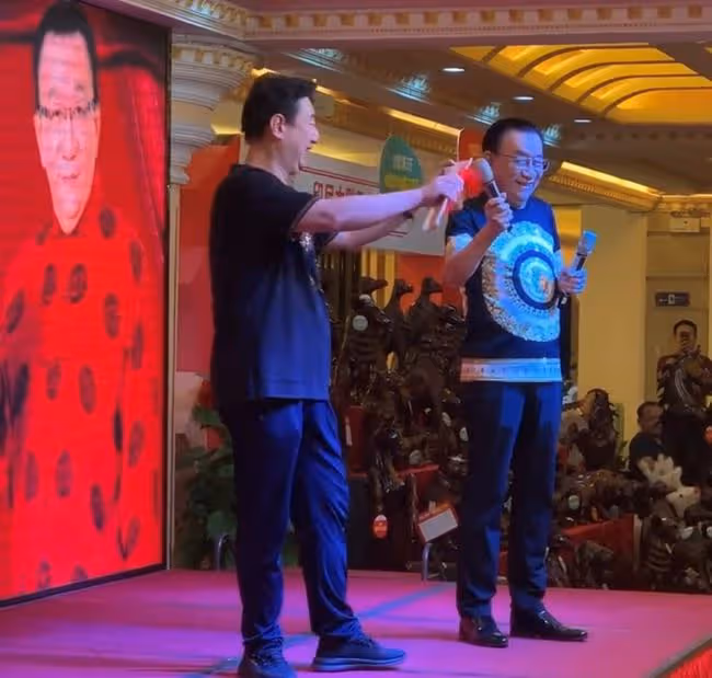 75歲侯耀華現身商演,舉倆話筒為他人當人體支架,抿嘴微笑顯尷尬