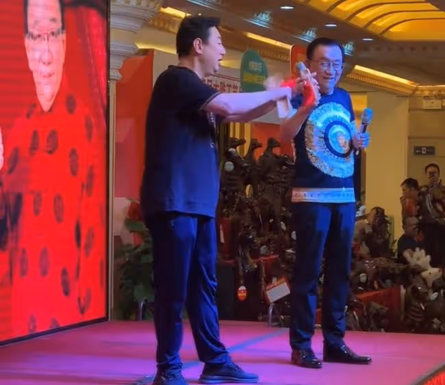 75歲侯耀華現身商演,舉倆話筒為他人當人體支架,抿嘴微笑顯尷尬