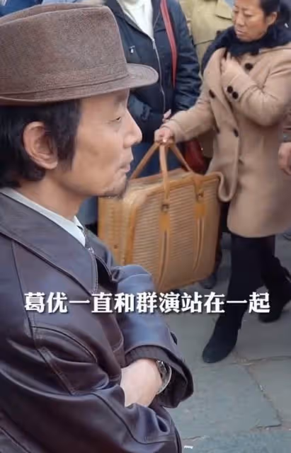 64歲葛優給群演大媽讓座，態度謙和雙手捧上，陪同群演站立等候