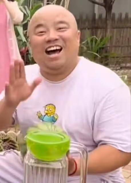 馮鞏攜徒弟送夏至祝福,頭髮稀疏眼紋明顯,身後粉衣女吹嗩吶搶鏡