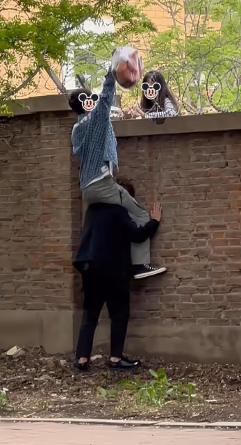 男子騎在兄弟的脖子上，隔著圍牆給女友送吃的：不夠吃我再給你買