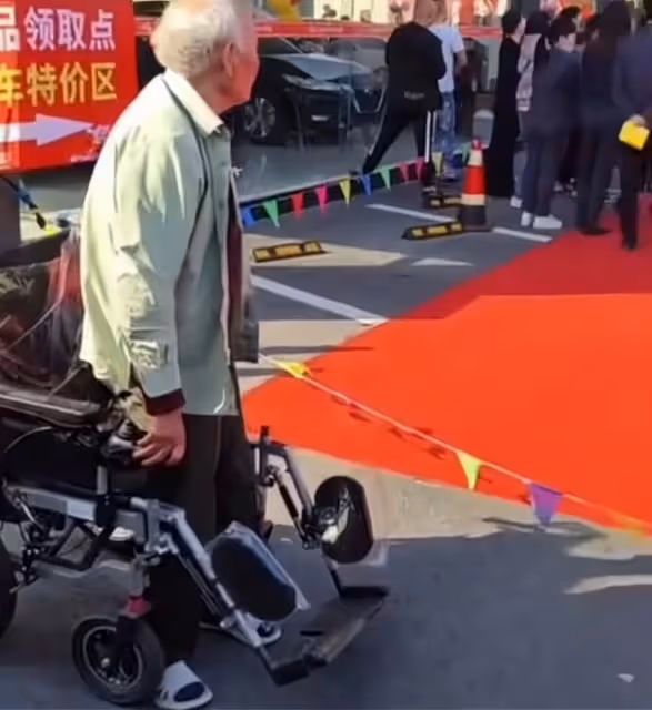 車模在台上表演,坐在輪椅上的大爺離太遠看不清,一著急站了起來