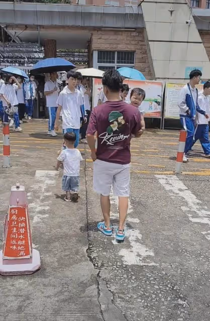 44歲年輕爺爺,抱著孫女牽著孫子去學校接兒子放學,遭兒子嫌棄