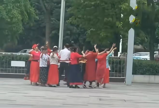 大爺和一群大媽跳舞,幾個坐輪椅大爺遠遠觀看,羨慕的眼神藏不住
