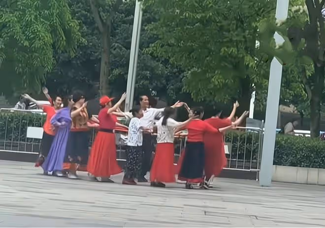大爺和一群大媽跳舞,幾個坐輪椅大爺遠遠觀看,羨慕的眼神藏不住