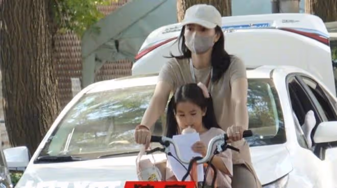 高圓圓騎單車接女兒放學，卡其色短袖長裙搭配棕色瑜伽褲，休閒美