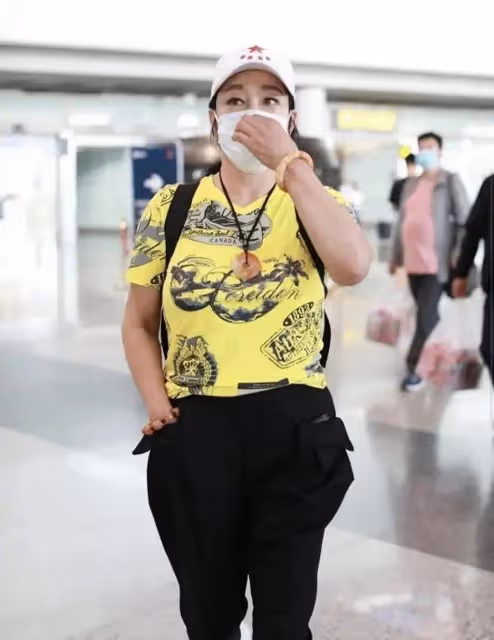 劉曉慶現身機場,穿修身褲雙腿纖細胯太大,一身明黃色T恤真顯黑