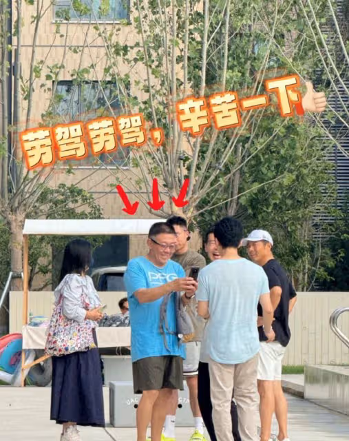 李健幫阿那亞村長拍照,大方端著手機半蹲著,老婆孟小蓓戴著口罩