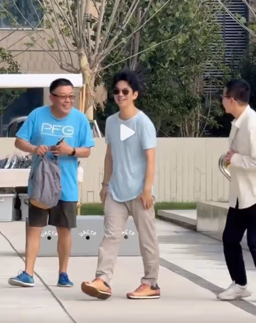 李健幫阿那亞村長拍照,大方端著手機半蹲著,老婆孟小蓓戴著口罩