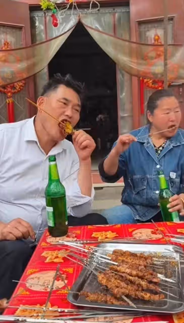 大衣哥帶老婆吃燒烤,邊吃肉串邊喝酒,表情十分滿足