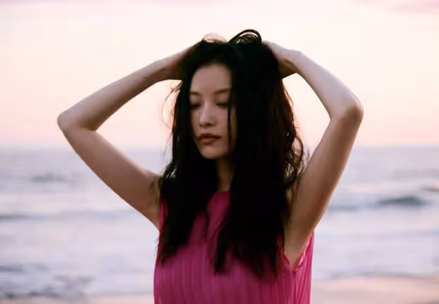 倪妮玫紅裙海邊漫步，嘴銜鮮花眼神撩人：這是何等的風情萬種！