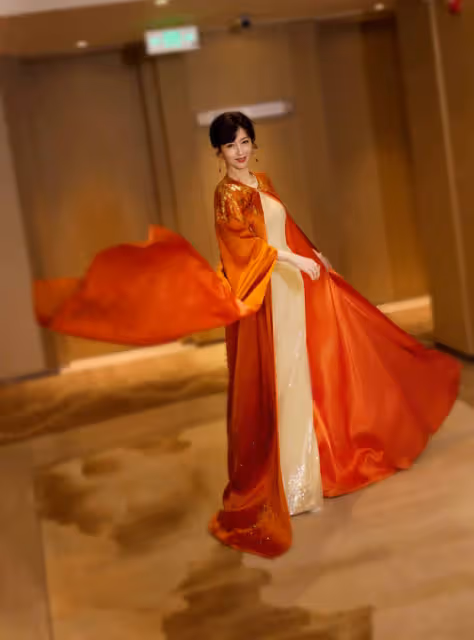 趙雅芝穿橙色長袍雍容華貴，手持團扇似古代仕女