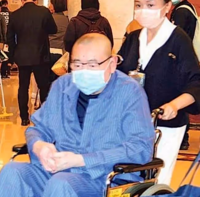 71歲劉鑾雄出行，曾換腎走路小心翼翼，1人攙扶他2人撐傘陣仗大