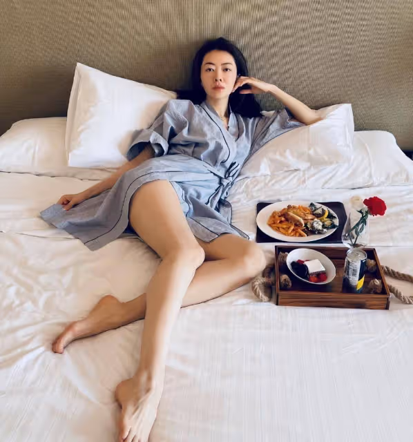 42歲熊黛林躺床上用餐!穿浴袍側面開叉秀美腿,休閒度假生活愜意