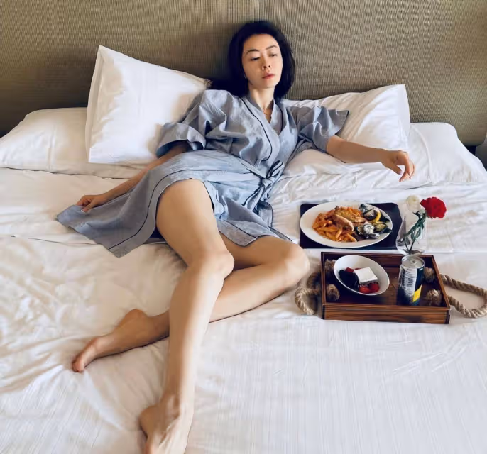 42歲熊黛林躺床上用餐!穿浴袍側面開叉秀美腿,休閒度假生活愜意
