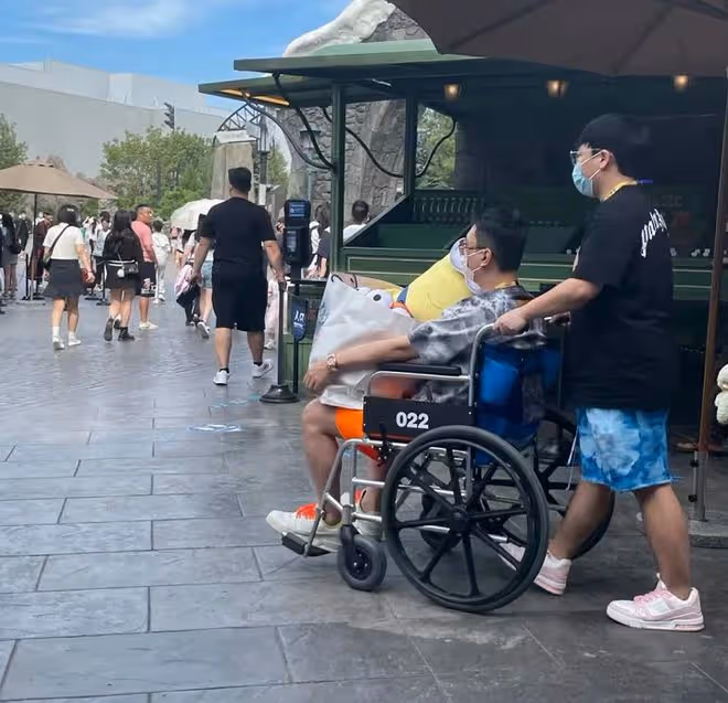王思聰坐輪椅逛遊樂園引熱議!蹺二郎腿被人推著走,身邊美女環繞