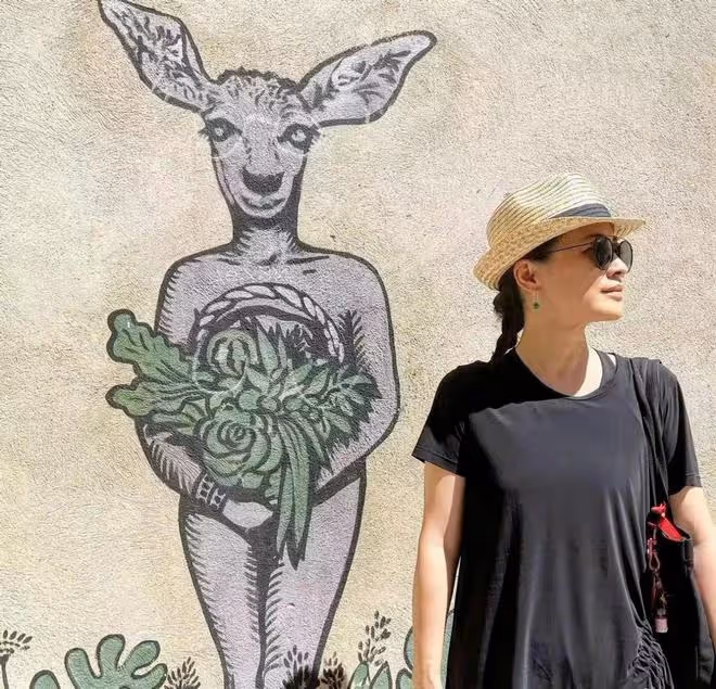 47歲梅婷罕現身!穿黑棉襖打扮樸素開心大笑,素顏模仿戲劇節海報