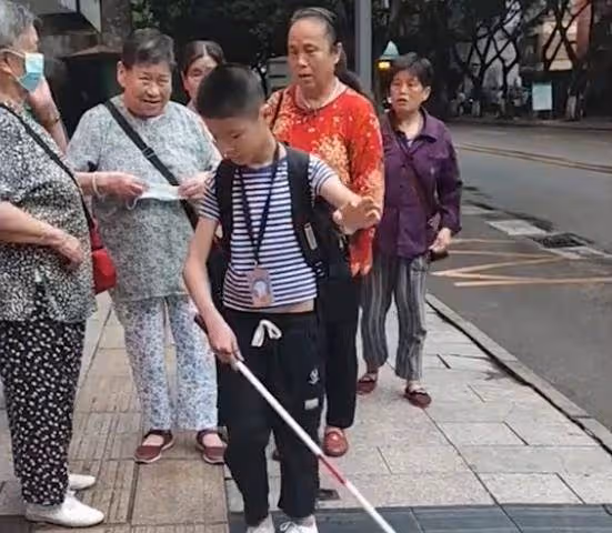 眼盲男孩獨自去上學，媽媽悄悄跟隨保護，路人默默伸出援手