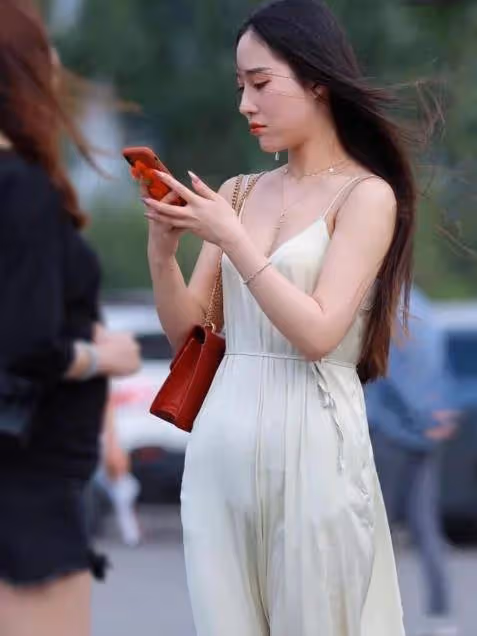 美女一身凈白弔帶連衣裙，微風吹拂下裙擺飛揚，美不勝收