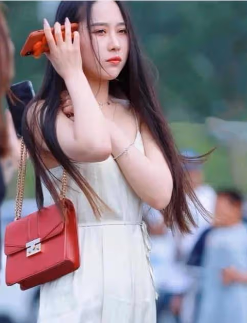 美女一身凈白弔帶連衣裙，微風吹拂下裙擺飛揚，美不勝收