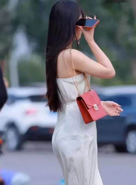 美女一身凈白弔帶連衣裙，微風吹拂下裙擺飛揚，美不勝收