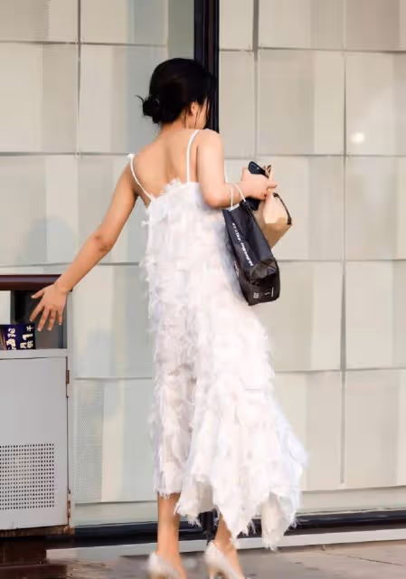 路人街拍，小姐姐身穿一件白色的弔帶連衣裙，很有仙女氣
