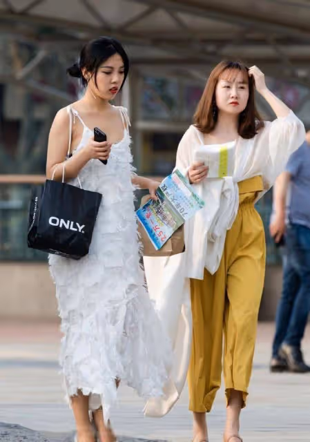 路人街拍，小姐姐身穿一件白色的弔帶連衣裙，很有仙女氣