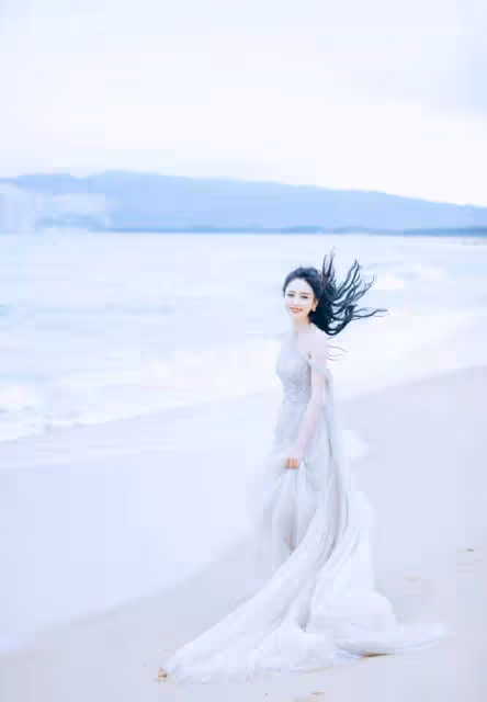 佟麗婭海邊漫步，身穿銀色閃亮紗裙顯曼妙身姿，如銀河飄落的仙女