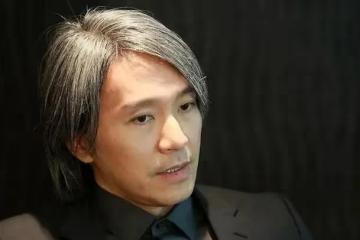 周星馳在辦公室寫「心想事成」符,桌子上擺著李小龍和他的功夫照