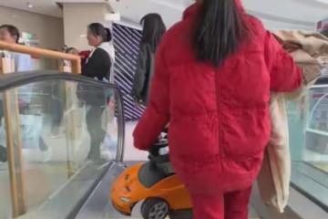 女孩抬著弟弟的車,拿著衣服坐扶梯,網友:二胎家庭做姐姐不容易