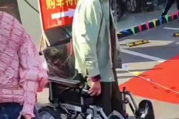 車模在台上表演,坐在輪椅上的大爺離太遠看不清,一著急站了起來