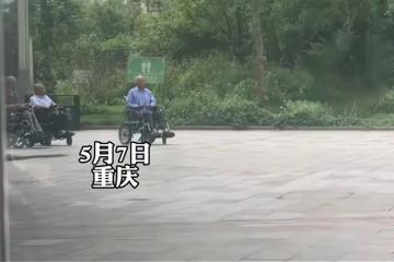 大爺和一群大媽跳舞,幾個坐輪椅大爺遠遠觀看,羨慕的眼神藏不住
