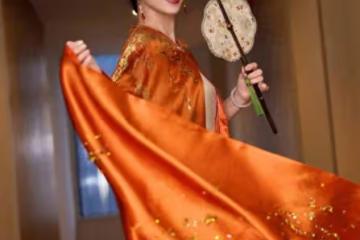 趙雅芝穿橙色長袍雍容華貴，手持團扇似古代仕女